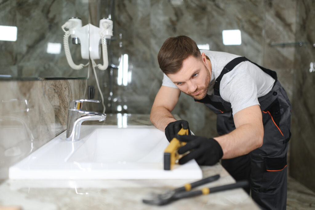 Contractor measuring vanity in modern bathroom renovation