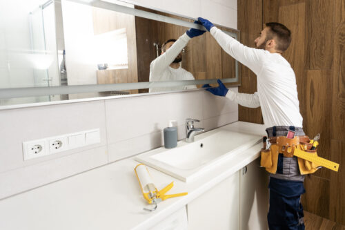 Contractor installing mirror during small bathroom remodel