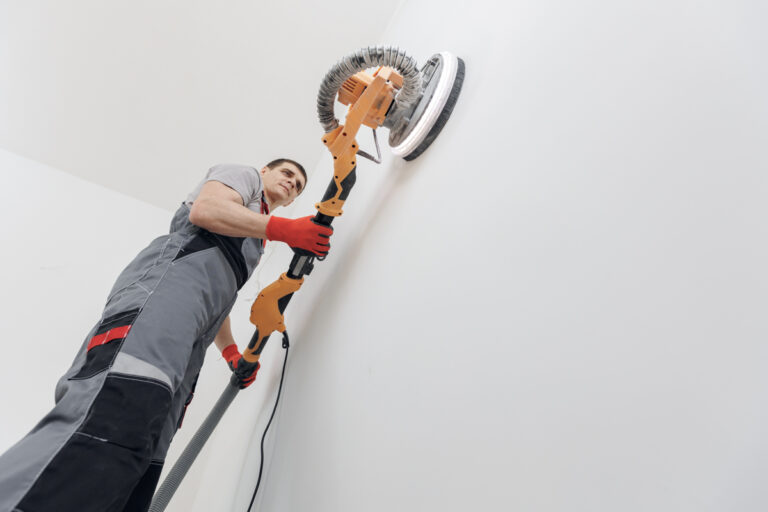 Contractor sanding ceiling during popcorn ceiling removal DIY