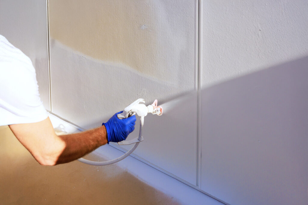 Contractor spraying wall near vinyl plank flooring installation