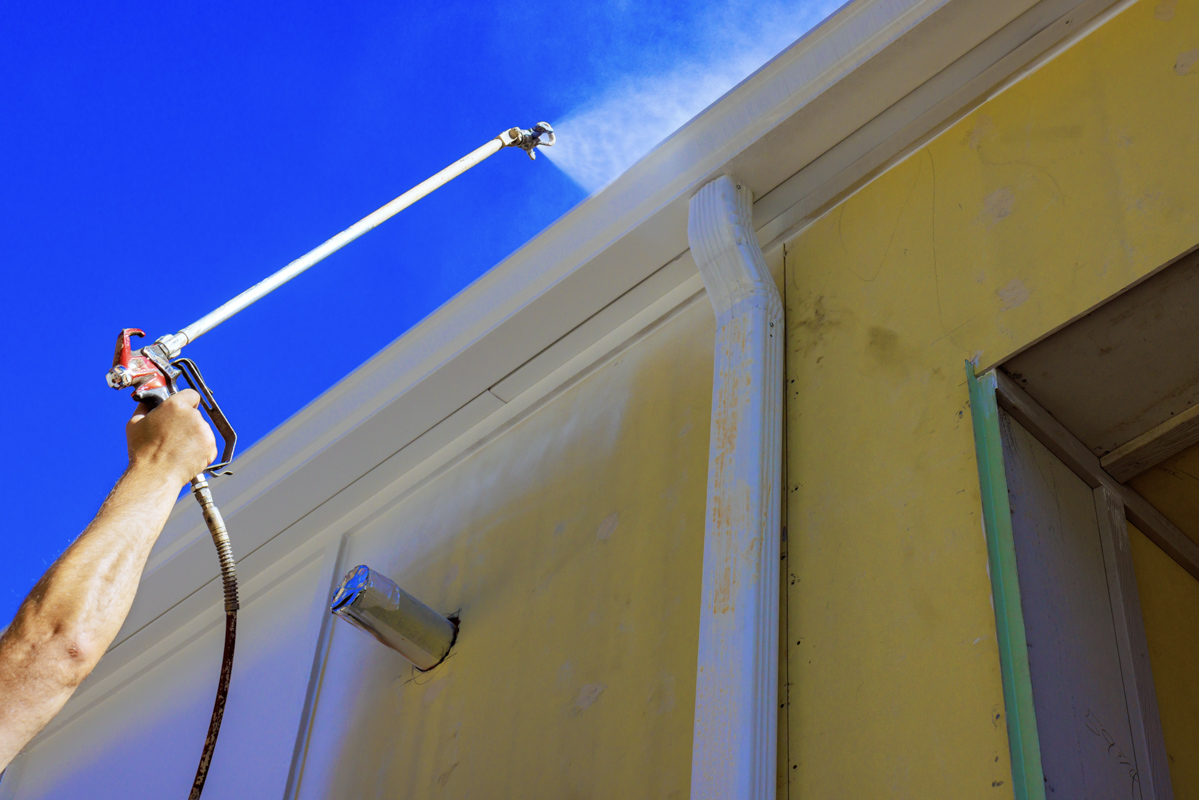 Contractor spraying exterior trim during full home renovation