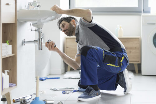 Contractor repairing sink in modern porcelain tile bathroom