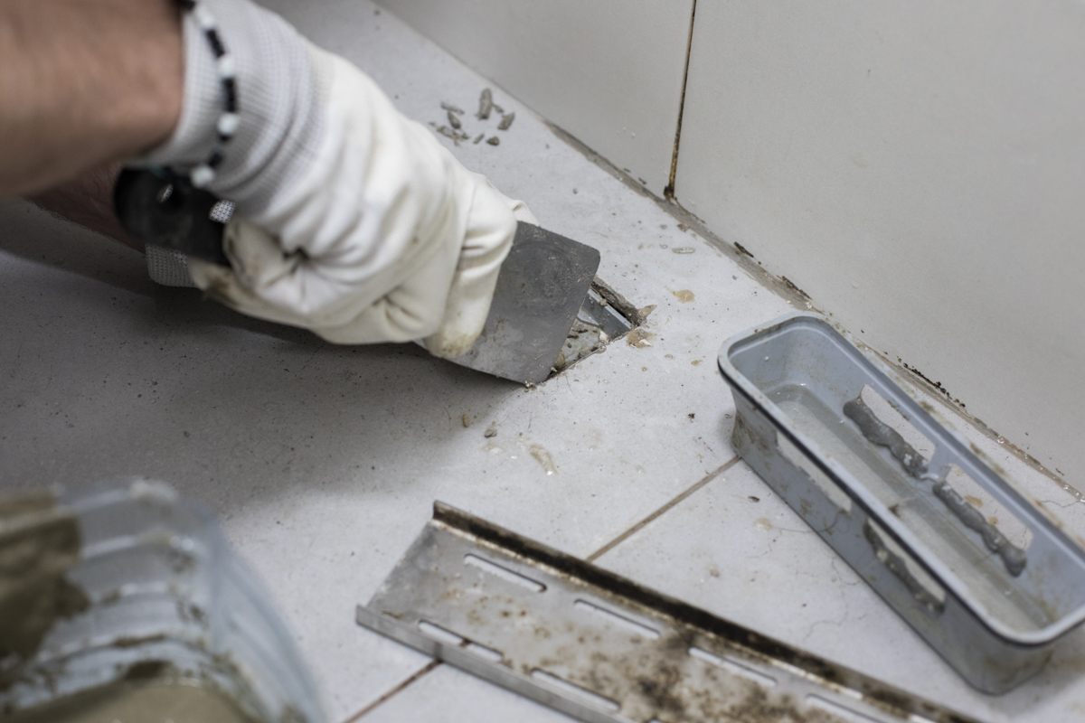 Cleaning grout in a walk-in tiled shower during bathroom renovation