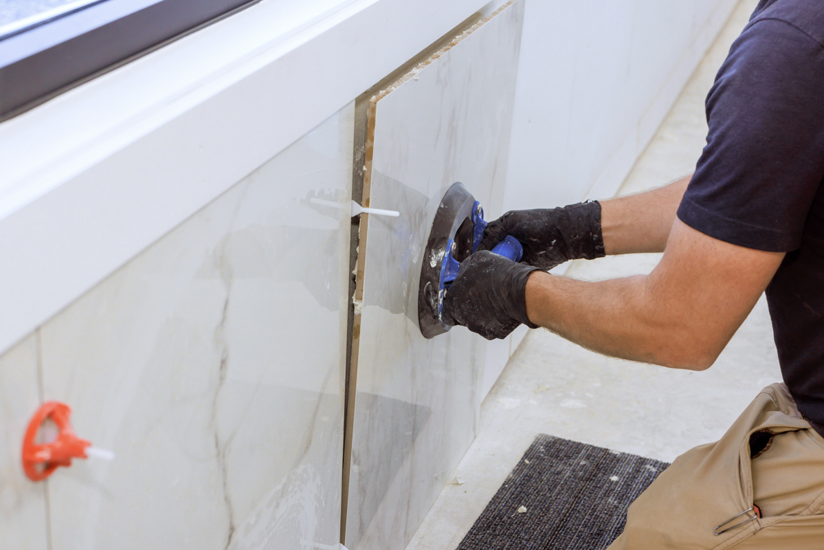 Contractor installing porcelain shower tile in bathroom