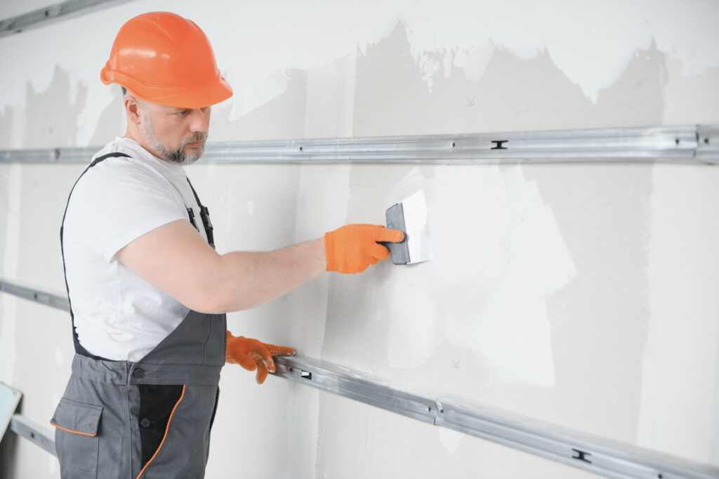Contractor scraping wall before popcorn ceiling asbestos test