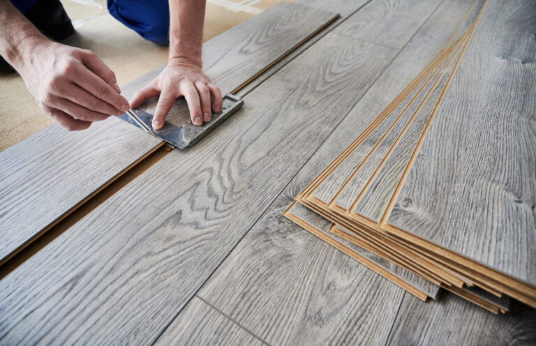 Laminate vs vinyl flooring installation with gray wood-look planks