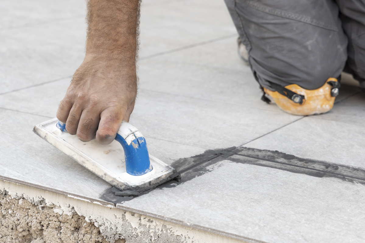 Contractor smoothing grout during vinyl plank flooring installation