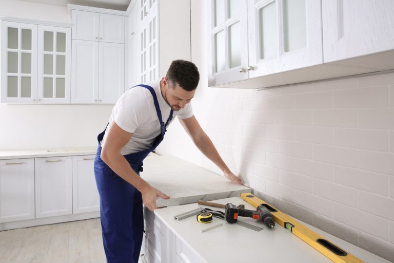 Contractor installing modern kitchen backsplash tile in white kitchen
