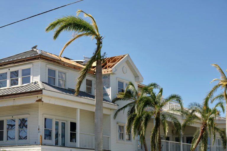 Storm-damaged home showing Florida HVHZ roof damage and windows