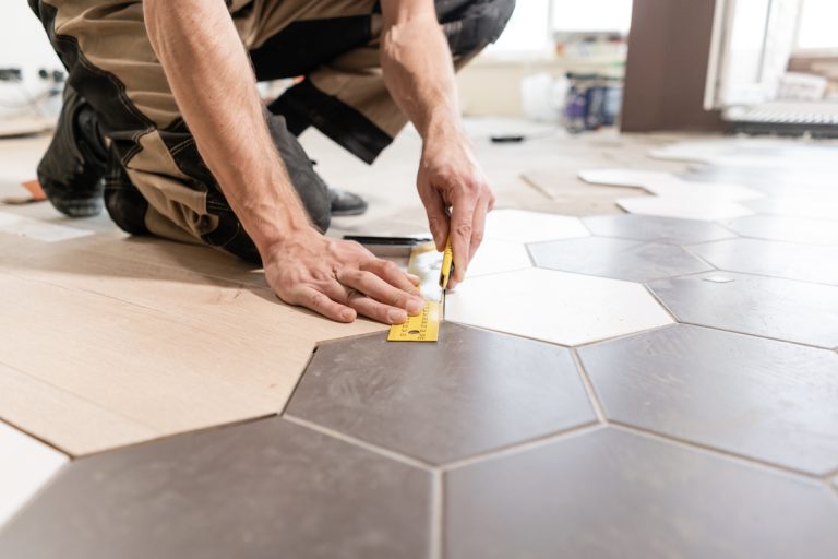 Contractor installing tile in modern black cabinets kitchen remodel
