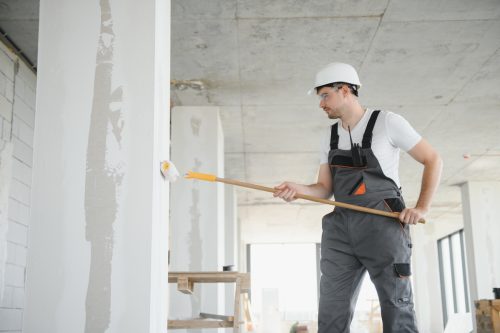 Contractor painting walls during home renovation prep for vinyl plank flooring