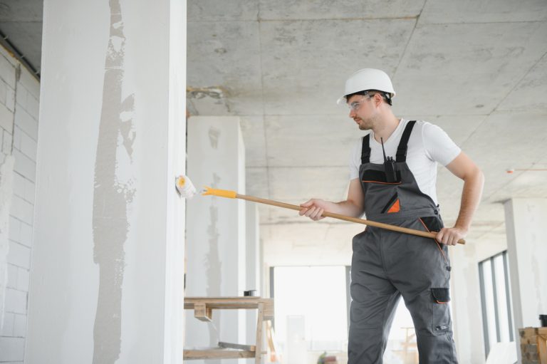 Contractor painting walls during home renovation prep for vinyl plank flooring