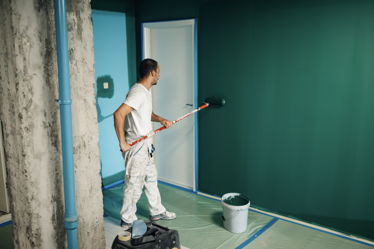 Contractor painting interior wall during home renovation prep