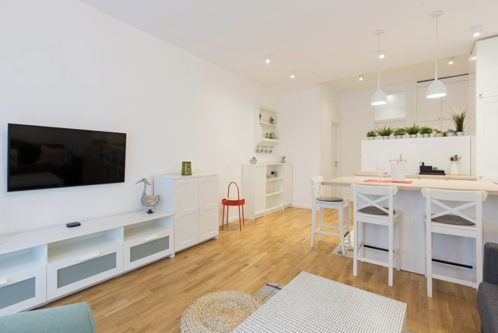 Open-concept condo renovation with white kitchen and wood floors