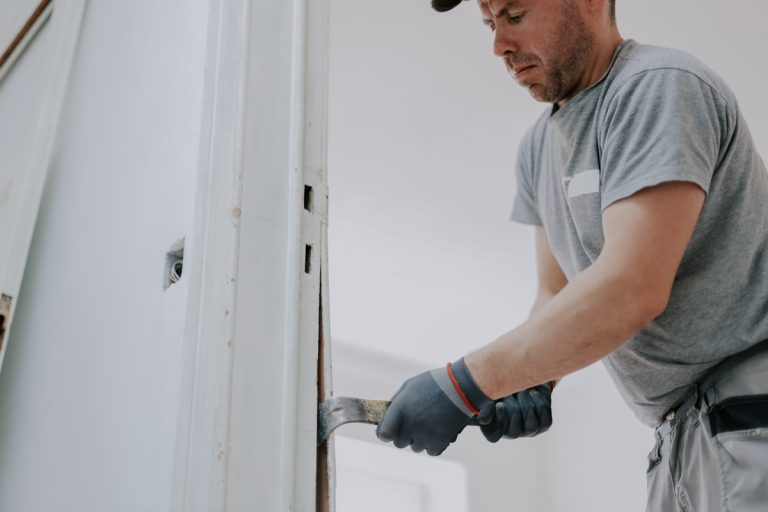 Contractor adjusting a sliding glass door frame with pry bar