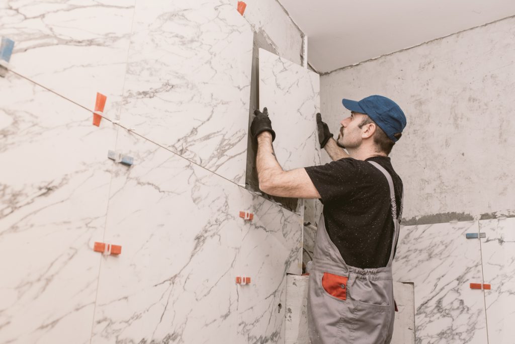 Contractor installing marble-look shower tile for bathroom renovation