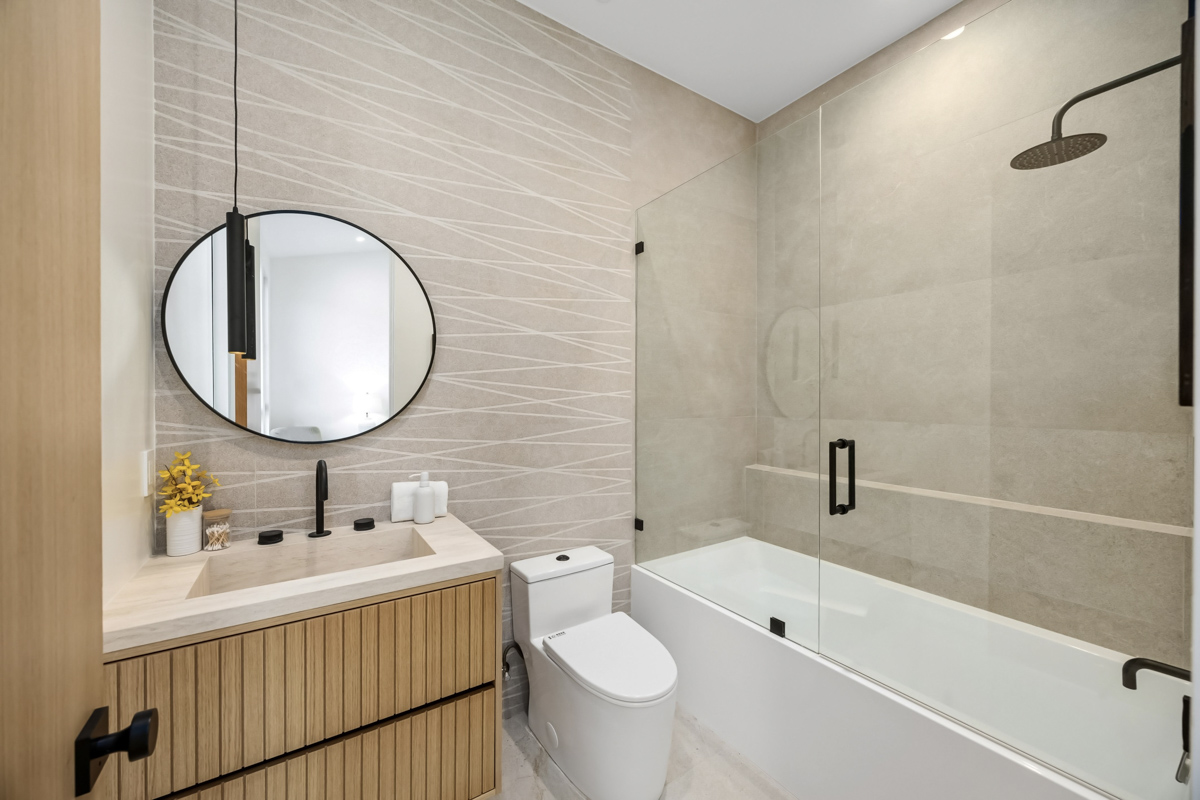 Frameless shower glass door in modern bathroom with black fixtures