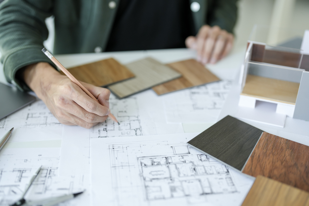 Designer planning kitchen remodeling with floor plans and wood samples